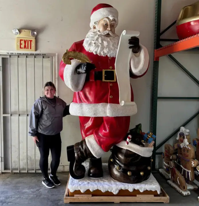 Person standing next to a large Santa Claus statue in an indoor setting.
