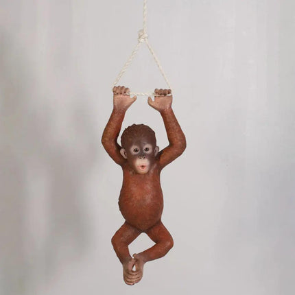 Orangutan figurine hanging from a rope on a plain background
