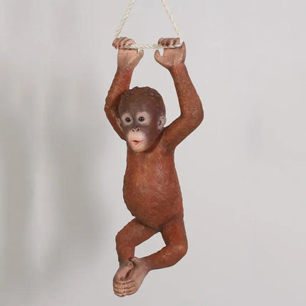 Orangutan figurine hanging from a rope on a plain background