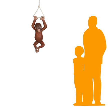 Small monkey toy hanging from a string with orange silhouette figures of a man and child on a white background.