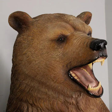 Brown bear head sculpture with an open mouth on a plain background