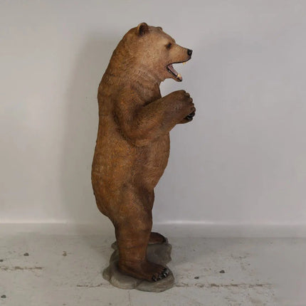 Brown bear statue standing on its hind legs against a white wall.