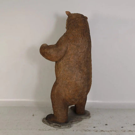 Rust-colored bear statue on a white floor against a white wall