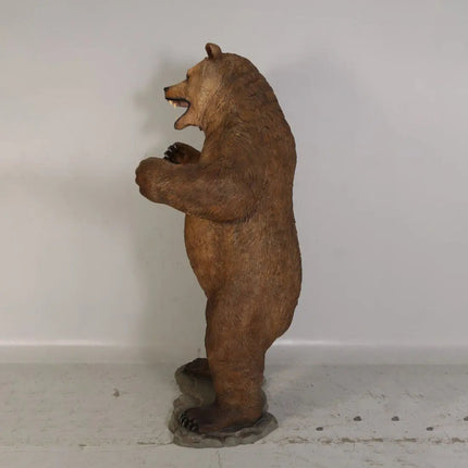 Brown bear statue standing on its hind legs against a white wall.