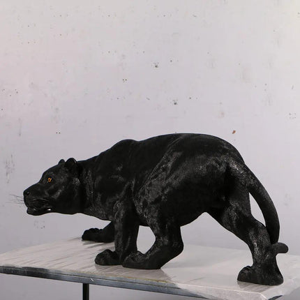 Black panther statue on a marble base against a gray wall