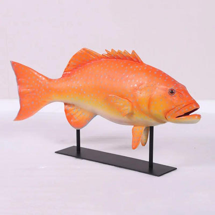 Orange fish model on a black stand against a white background