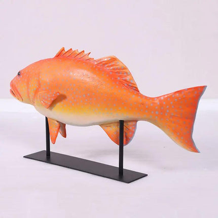 Orange fish model on a black stand against a white background